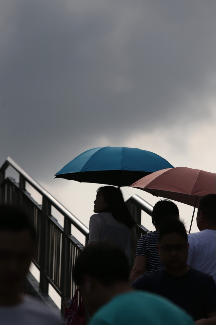 4月22日,深圳华强路地铁站附近,打伞遮阳的行人.